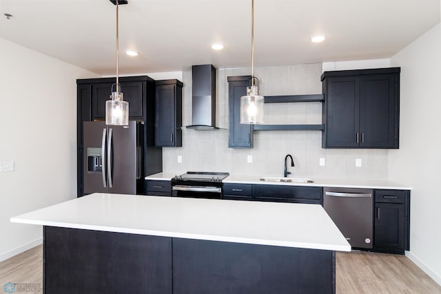 kitchen featuring appliances with stainless steel finishes, a center island, hanging light fixtures, sink, and wall chimney range hood