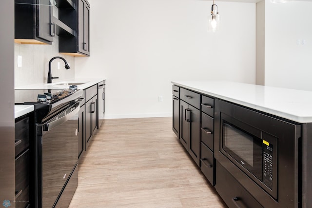 kitchen featuring pendant lighting, stainless steel electric range oven, light hardwood / wood-style flooring, sink, and black microwave