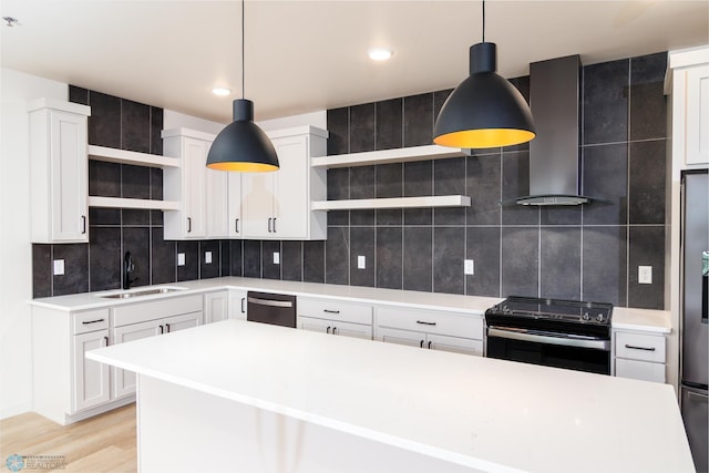 kitchen featuring decorative light fixtures, stainless steel appliances, light hardwood / wood-style flooring, and wall chimney exhaust hood