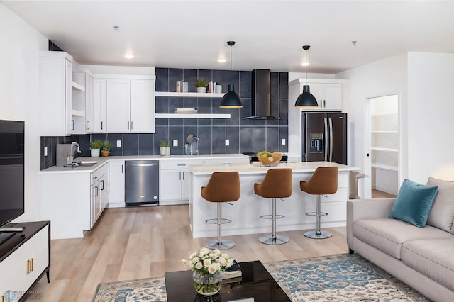 kitchen featuring white cabinets, hanging light fixtures, light wood-type flooring, tasteful backsplash, and stainless steel appliances