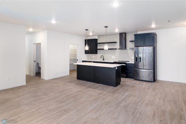 kitchen with a center island, decorative light fixtures, light wood-type flooring, appliances with stainless steel finishes, and wall chimney range hood