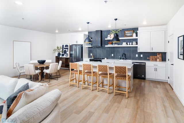 kitchen with light countertops, a sink, open shelves, dishwashing machine, and stainless steel refrigerator with ice dispenser