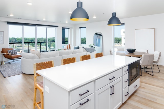 kitchen with black microwave, pendant lighting, plenty of natural light, and white cabinetry