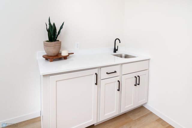 interior space featuring sink, light wood-type flooring, and white cabinets