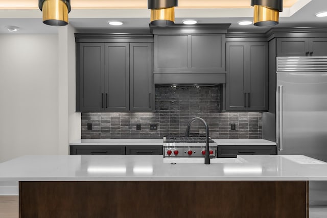 kitchen featuring decorative backsplash, light stone counters, stainless steel built in refrigerator, and a kitchen island with sink