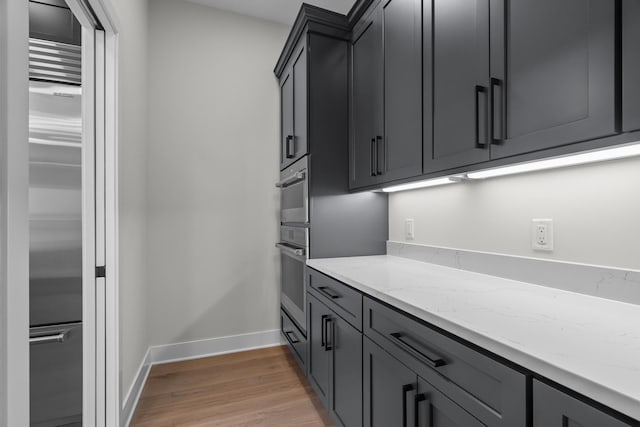 kitchen with light wood-type flooring, stainless steel appliances, and light stone counters