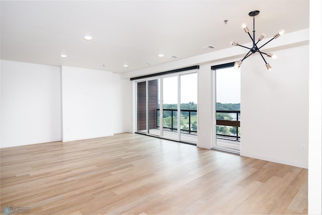 empty room featuring light hardwood / wood-style floors and a notable chandelier