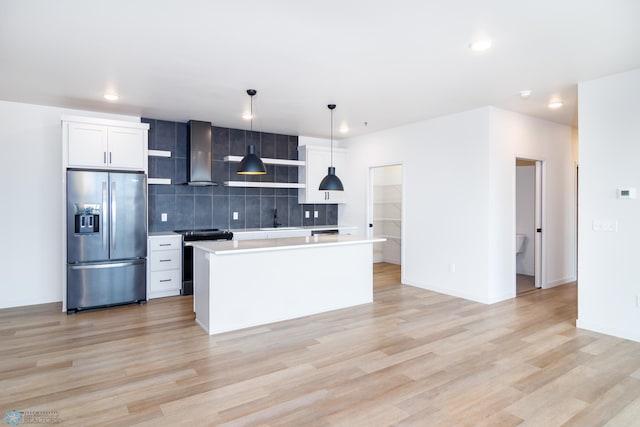 kitchen featuring range with electric cooktop, stainless steel fridge, an island with sink, pendant lighting, and light wood-type flooring