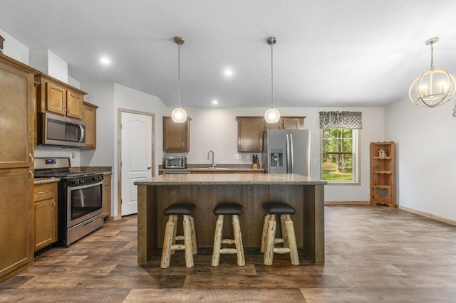 kitchen featuring appliances with stainless steel finishes, dark wood-style flooring, a kitchen bar, a center island, and recessed lighting