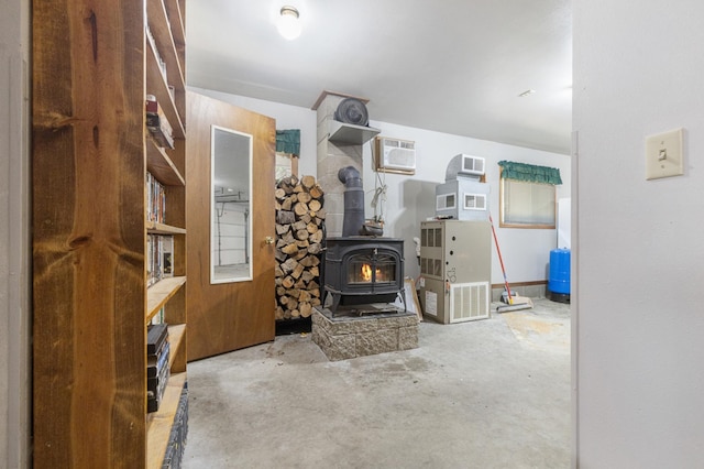 living room featuring a wood stove, unfinished concrete floors, and an AC wall unit