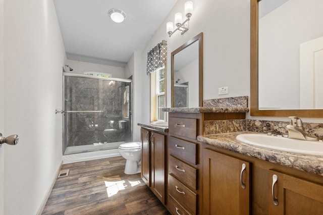 bathroom featuring vanity, toilet, hardwood / wood-style flooring, and a shower with shower door