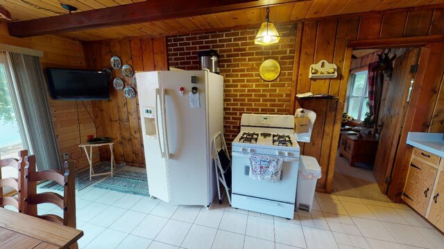 kitchen featuring wood walls, wooden ceiling, light tile patterned floors, and white appliances