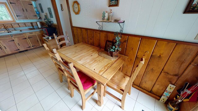 dining room with light tile patterned flooring, sink, and wood walls