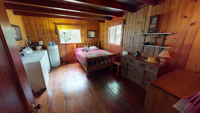 bedroom with wood walls, washer and clothes dryer, beamed ceiling, and hardwood / wood-style flooring