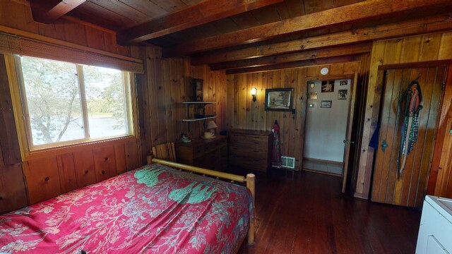 bedroom featuring beam ceiling, dark wood-type flooring, and wooden walls