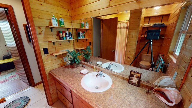 bathroom with tile patterned flooring, toilet, wooden walls, and vanity