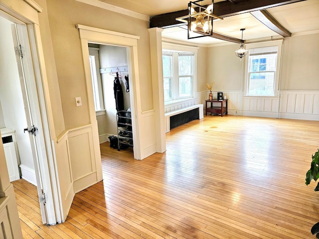 interior space with beam ceiling, light wood-type flooring, crown molding, and an inviting chandelier