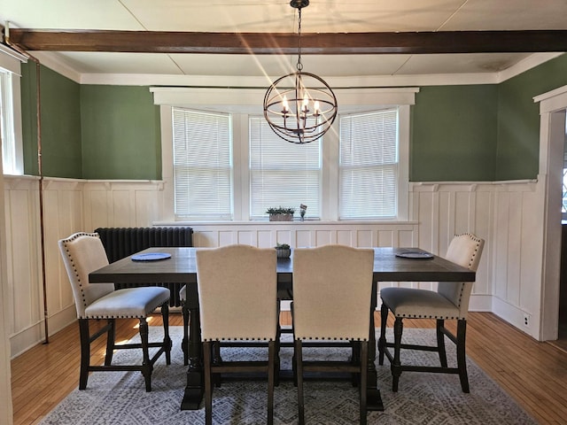 dining area with beam ceiling, hardwood / wood-style floors, and a notable chandelier