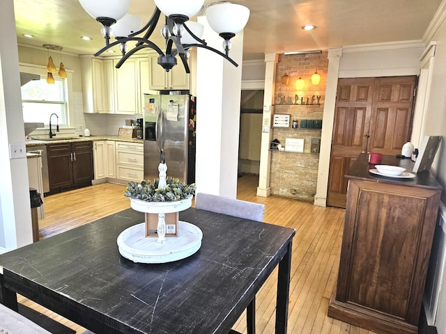 kitchen featuring sink, light wood-type flooring, cream cabinetry, a notable chandelier, and stainless steel fridge with ice dispenser