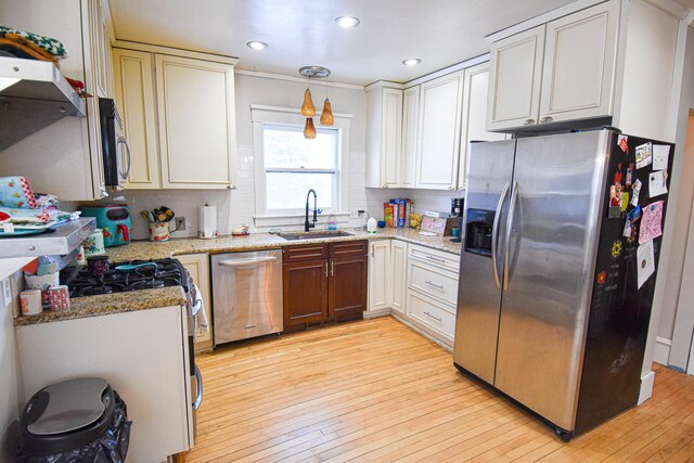 kitchen with sink, light wood-type flooring, decorative light fixtures, and appliances with stainless steel finishes