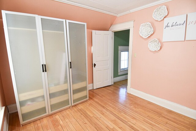 interior space featuring lofted ceiling, light wood-type flooring, and crown molding