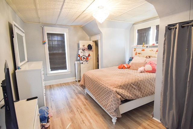 bedroom featuring radiator, light hardwood / wood-style flooring, and vaulted ceiling