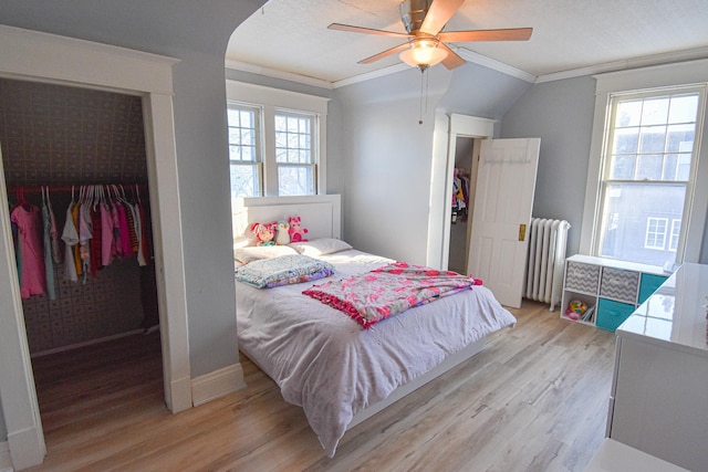 bedroom with radiator, ceiling fan, light hardwood / wood-style flooring, and multiple windows