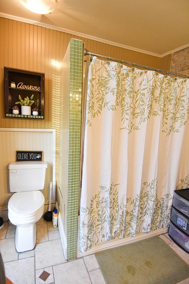 bathroom featuring toilet, crown molding, and wooden walls