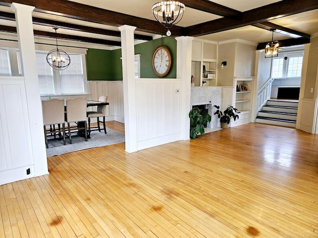721 Labree Ave N, Thief River Falls, MN 56701 - living area featuring a chandelier, wood-type flooring, beamed ceiling, a wainscoted wall, and stairway