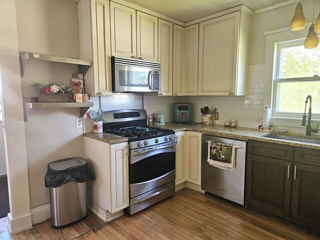721 Labree Ave N, Thief River Falls, MN 56701 - kitchen featuring appliances with stainless steel finishes, cream cabinets, a sink, light wood-style flooring, and decorative backsplash