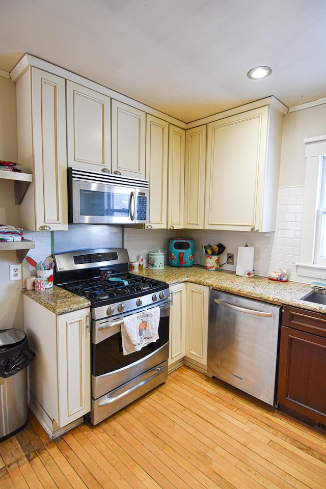 721 Labree Ave N, Thief River Falls, MN 56701 - kitchen with stainless steel appliances, light wood-style floors, cream cabinets, light stone counters, and open shelves