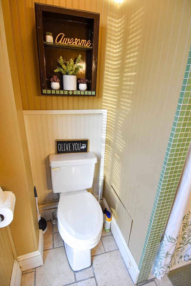 721 Labree Ave N, Thief River Falls, MN 56701 - bathroom featuring wooden walls, toilet, and stone finish floors