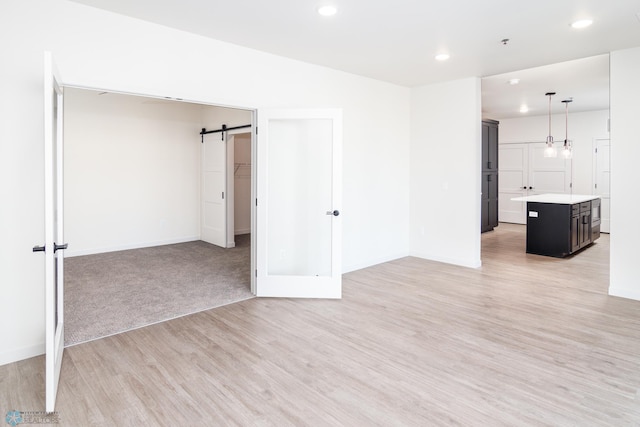 empty room with a barn door and light hardwood / wood-style flooring