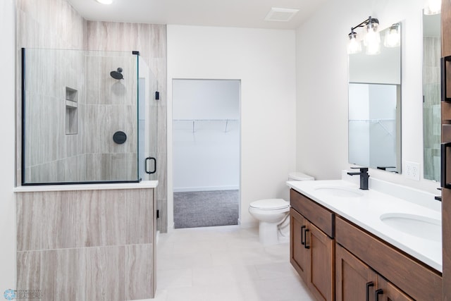 bathroom featuring tile patterned flooring, a shower with door, vanity, and toilet