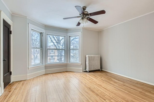 spare room featuring light hardwood / wood-style floors, ornamental molding, ceiling fan, and radiator