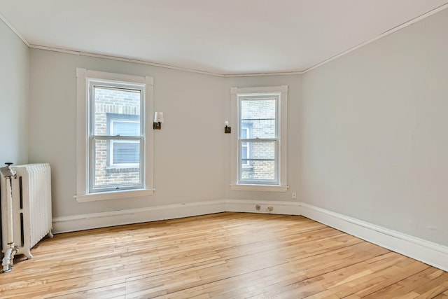 unfurnished room featuring ornamental molding, light wood-type flooring, and radiator heating unit