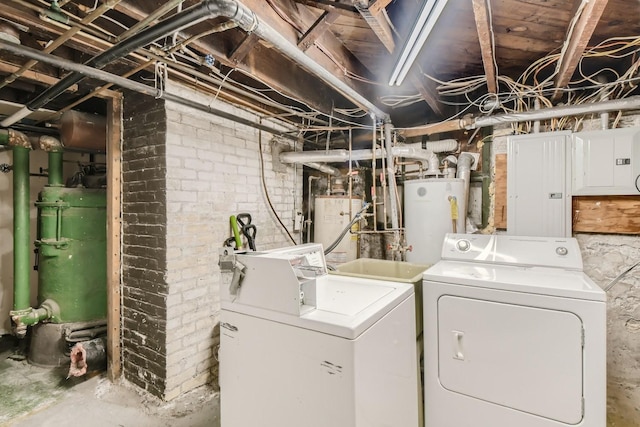 clothes washing area featuring electric water heater, washer and dryer, and brick wall