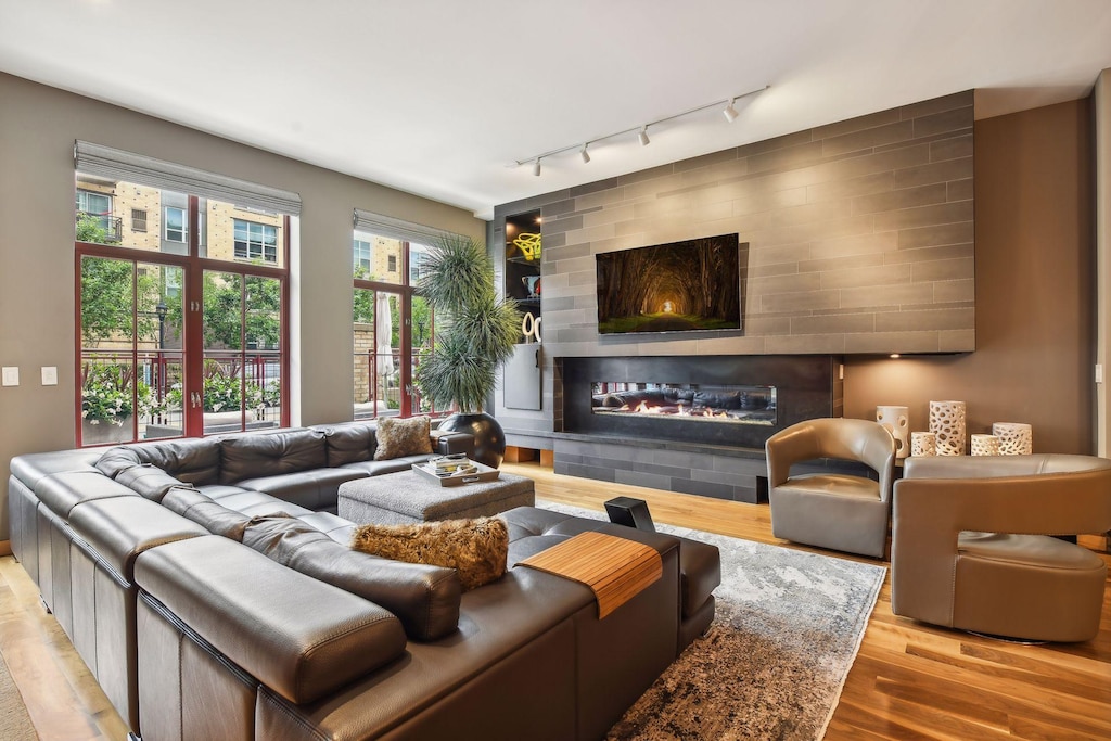 living room with rail lighting, light wood-type flooring, and a fireplace