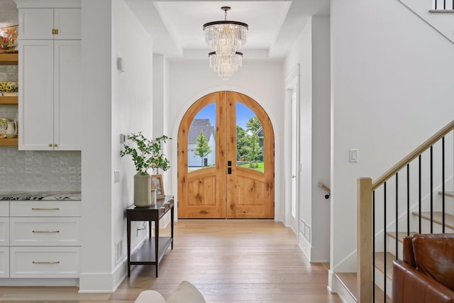 21412 Poate Ct, Rogers, MN 55374 - foyer entrance featuring stairs, a chandelier, light wood finished floors, a tray ceiling, and baseboards