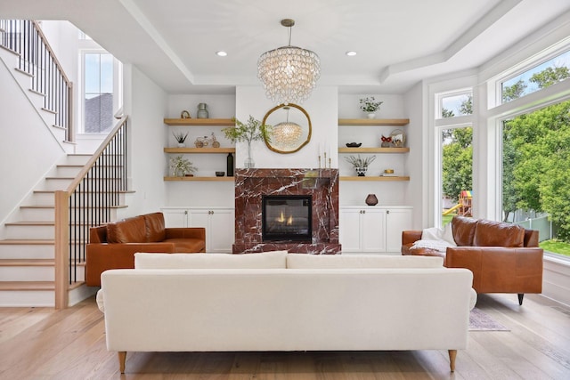 living room with a raised ceiling, a fireplace, a wealth of natural light, and light wood-type flooring