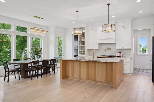21412 Poate Ct, Rogers, MN 55374 - kitchen featuring light stone counters, white cabinets, an island with sink, and decorative backsplash