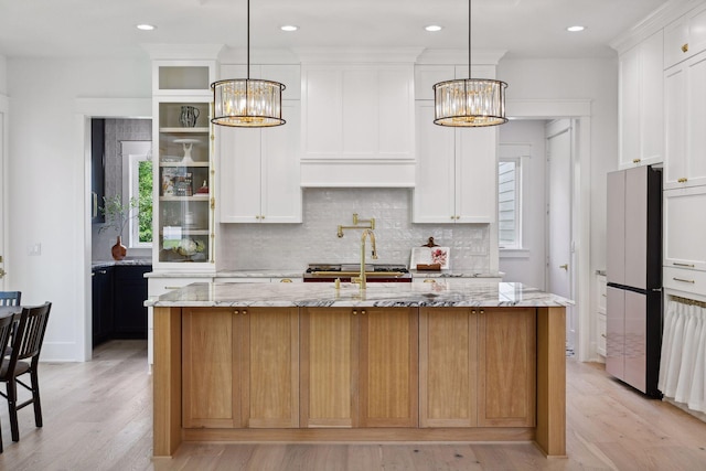 kitchen featuring light hardwood / wood-style floors, white cabinetry, a healthy amount of sunlight, and a kitchen island with sink