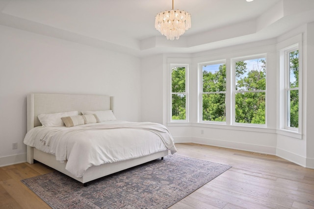 21412 Poate Ct, Rogers, MN 55374 - bedroom with a tray ceiling, a chandelier, baseboards, and light wood finished floors