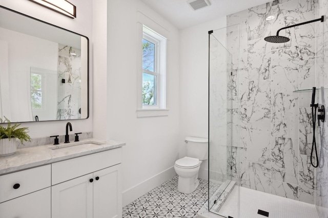 bathroom featuring vanity, tiled shower, tile patterned flooring, and toilet