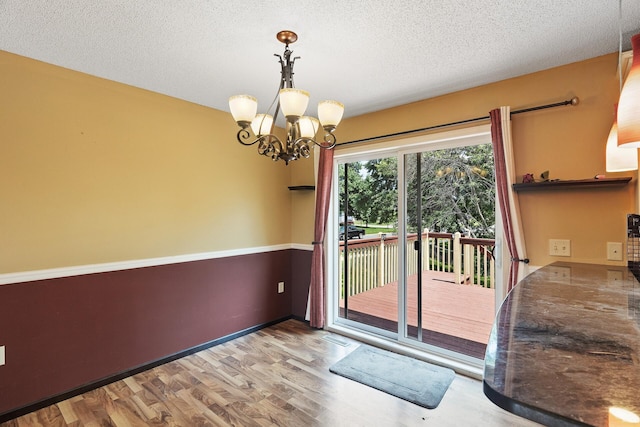 entryway featuring a textured ceiling, light wood-type flooring, and a chandelier