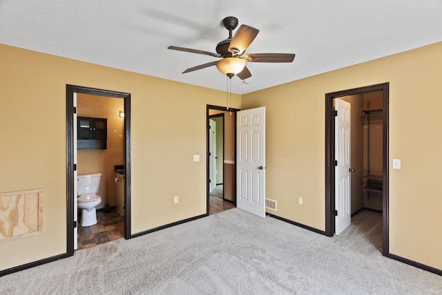 unfurnished bedroom with connected bathroom, a textured ceiling, light carpet, a spacious closet, and a closet