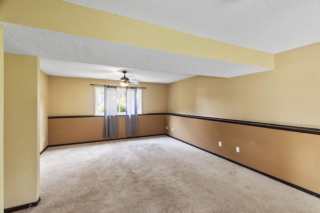 carpeted empty room with ceiling fan and a textured ceiling