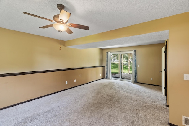 empty room featuring ceiling fan, light colored carpet, and a textured ceiling