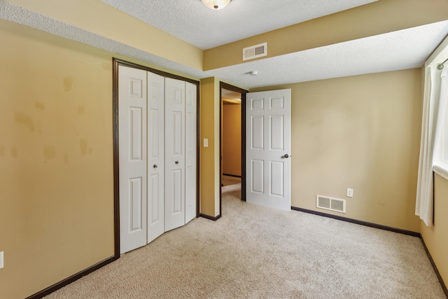 unfurnished bedroom featuring a closet, light carpet, and a textured ceiling