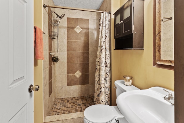 bathroom featuring sink, curtained shower, a textured ceiling, and toilet